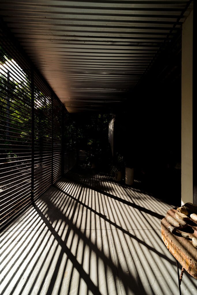 Pasillo con techo de listones y juego de sombras naturales en eco lodge en Boyacá.