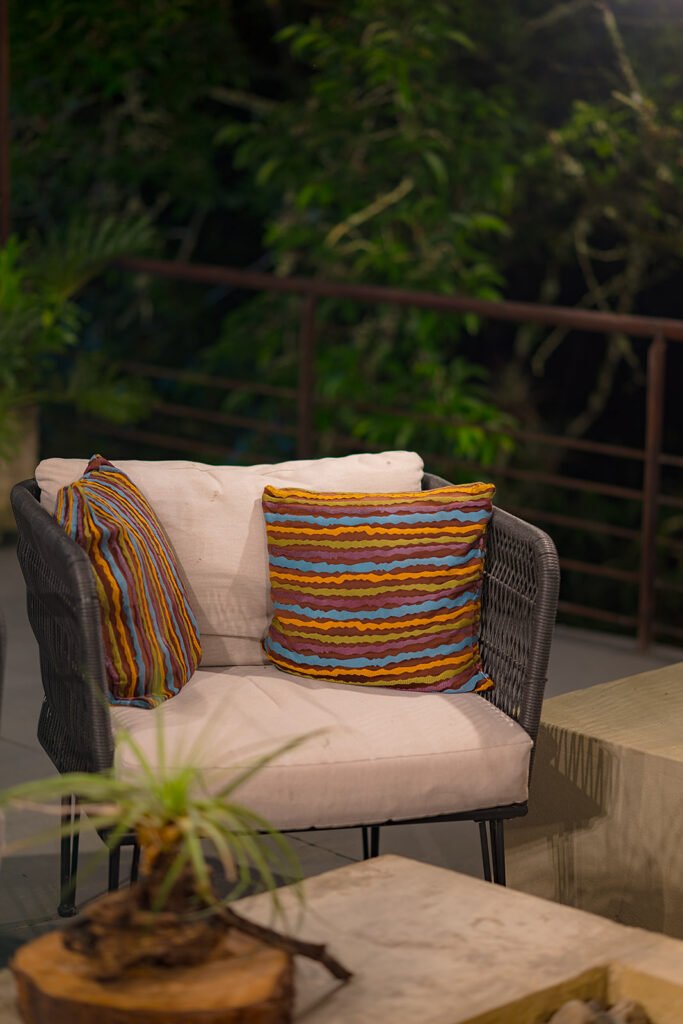 Sillón de exterior con cojines coloridos en zona de descanso del eco lodge Rivabella, Boyacá.