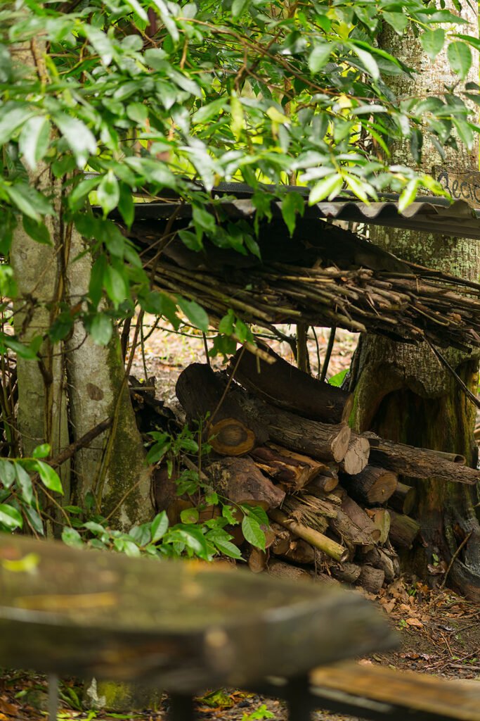 Pila de leña protegida bajo un refugio rústico entre árboles en Rivabella Eco Lodge, Valle de Tenza, Boyacá.