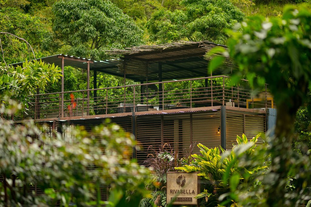 Vista exterior del eco lodge Rivabella rodeado de naturaleza en el Valle de Tenza, Boyacá, con terraza superior cubierta.